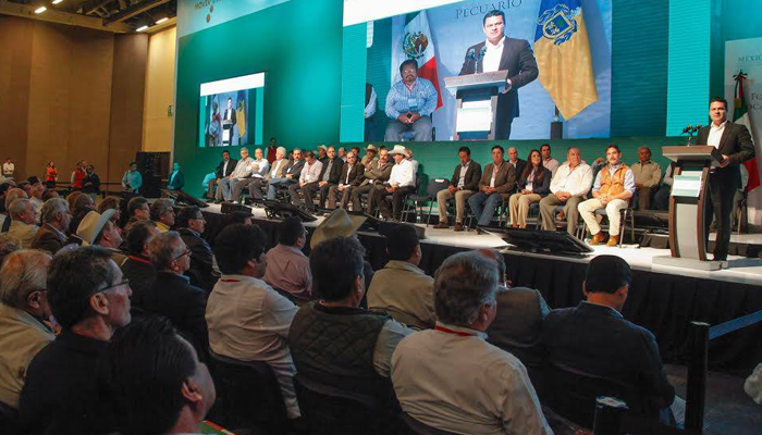 Foto donde muestra al gobernador Aristóteles Sandoval en un podium dando un discurso a varias personas dentro de un auditorio