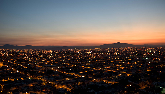 Foto panorámica de el Área Metropolitana de Guadalajara al atardecer con un cielo enrojecido.
